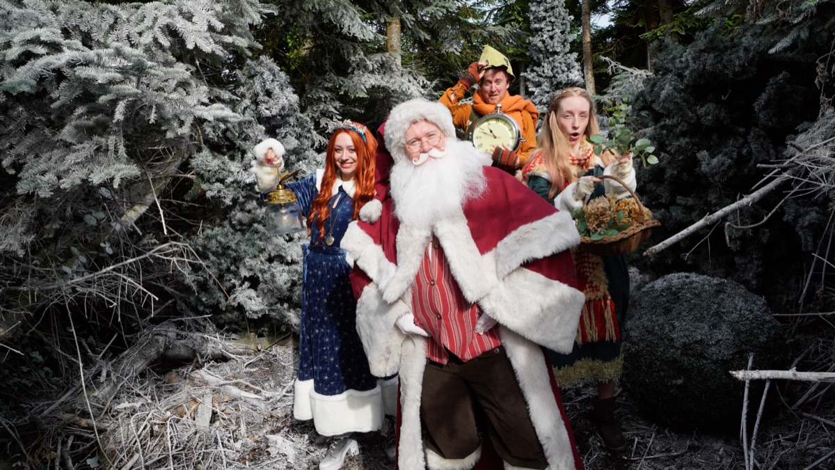 Father Christmas with three residents holding a festive basket in the forest